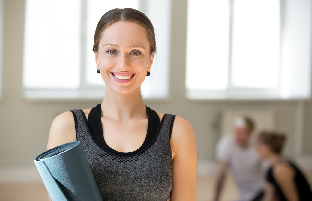 ヨガマットを抱えて笑顔の女性