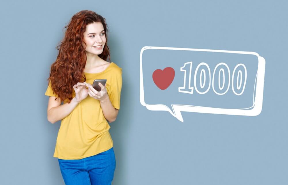スマートフォンを持った女性と1000いいねのサイン
