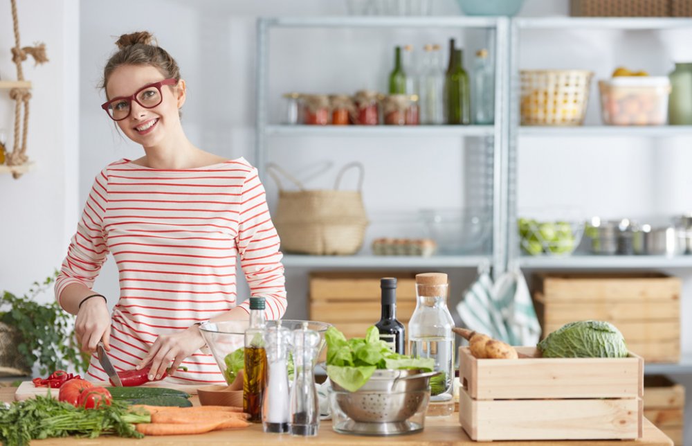 キッチンで野菜を手にして微笑む眼鏡をかけた女性