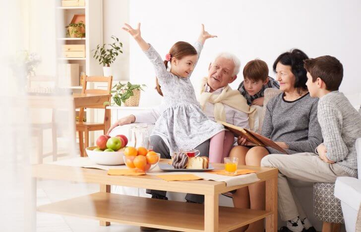 おじいちゃんおばあちゃんもそろった家族がソファで楽しそうに団らんしている