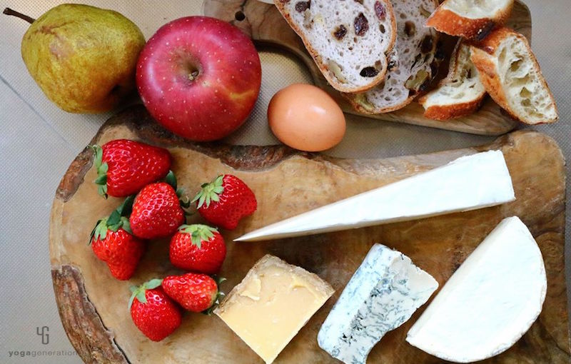 木製カットボードの上のチーズやフルーツやパン