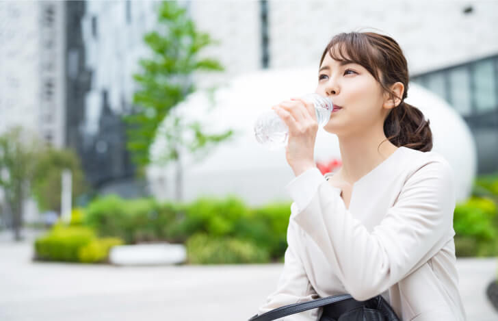 屋外で座って水を飲む女性