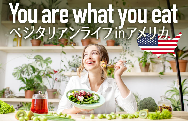 サラダプレートを手に持ち笑顔で食事する女性