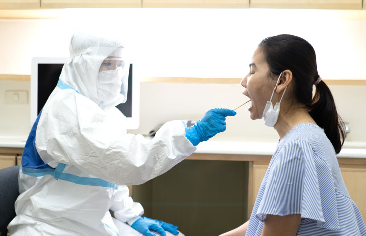 コロナウィルス感染検査で唾液を取られる女性