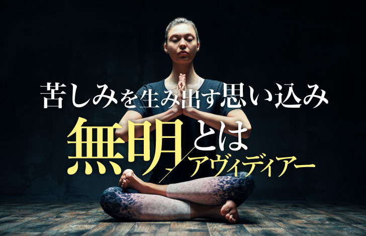 暗がりで明かりを受けて座るヨガ実践者の女性