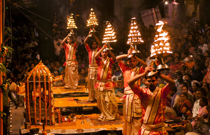 インドの男性たちが火が灯る飾り物を掲げて歩く宗教儀式の様子