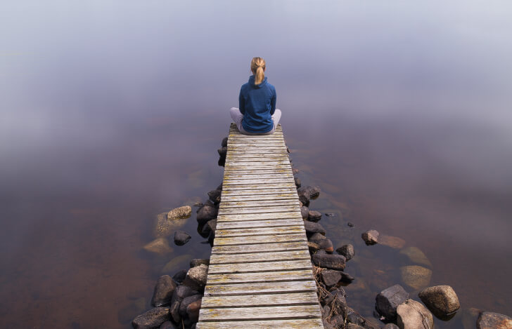 橋の先端に座り瞑想する女性
