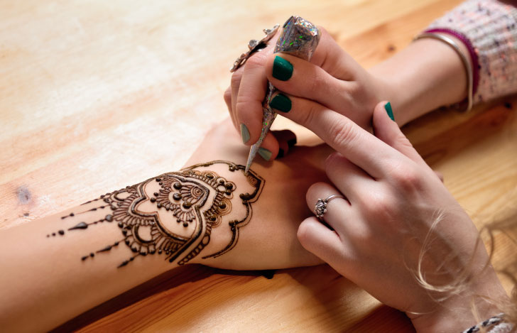 ヘナアーティストが女性の手首にヘナを施しているところ