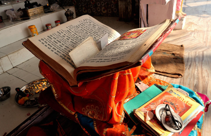 台の上に開かれた古いヨガの書物とティンシャ