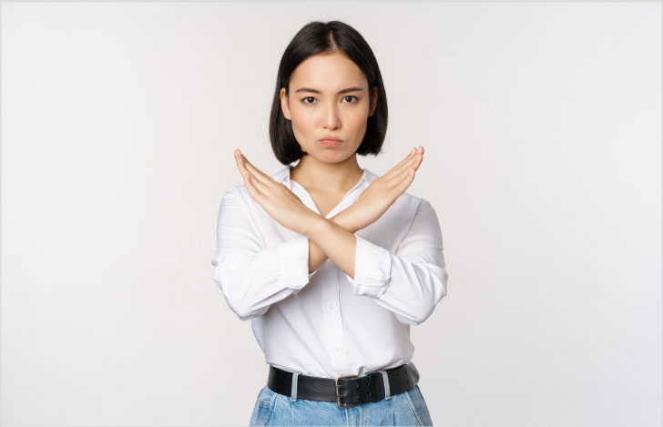 顔をしかめて手でバツ印を作る女性