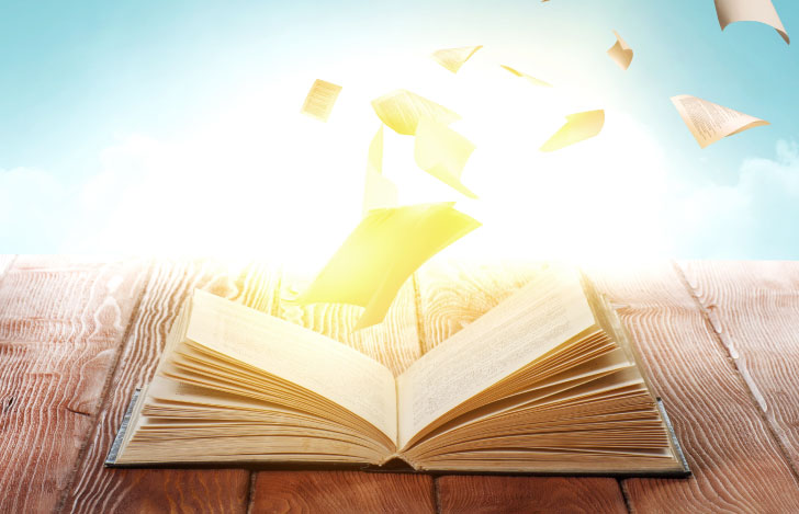 開いた本から飛び出す本のページを光