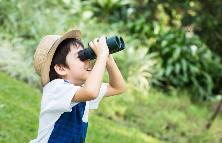自然の中で双眼鏡を除く帽子を被った少年