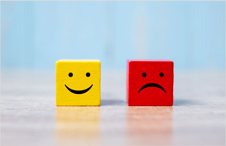 笑顔のイラストが描かれた黄色いキューブと困った顔のイラストが描かれた赤いキューブ