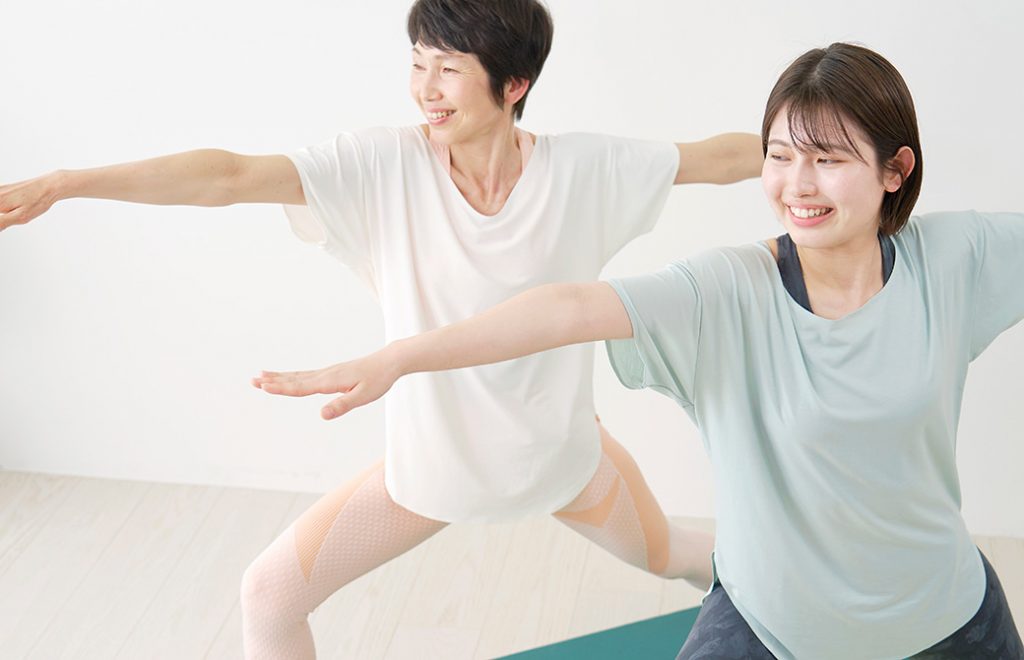 20代と50代の女性が戦士のポーズ２番を行なっている