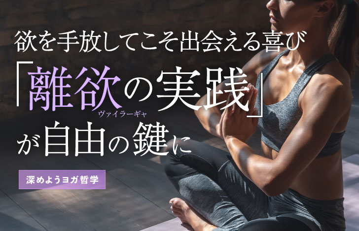 ヨガマットの上で安楽座で座り胸の前で合掌する女性