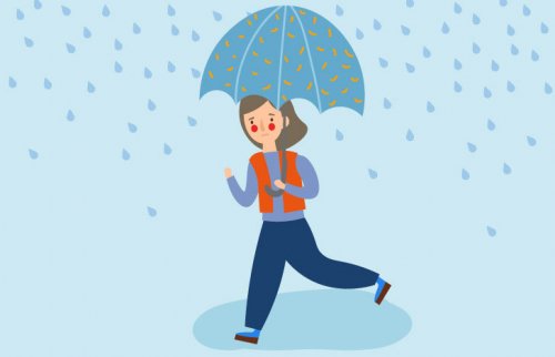 女性が雨のなか傘をさして歩いている