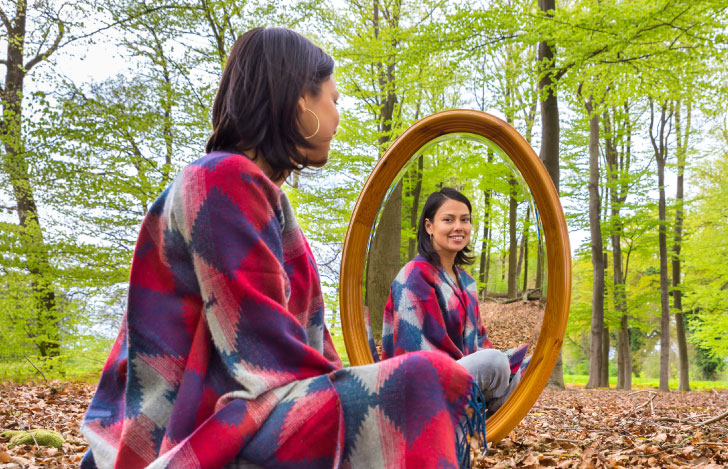 森の中で鏡に映る自分を見つめる女性
