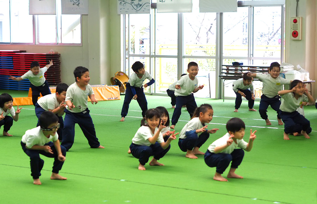 まり子先生と一緒にかにさんのポーズをする子供たち