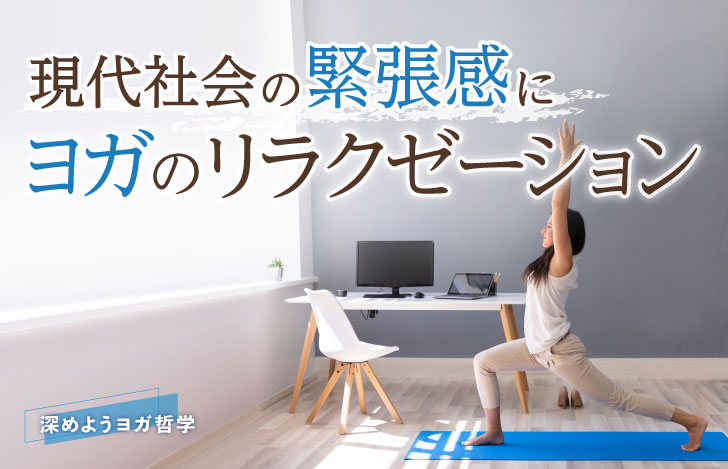 パソコンが置かれている机の前でヨガマットを敷いてヨガのアサナを練習する女性