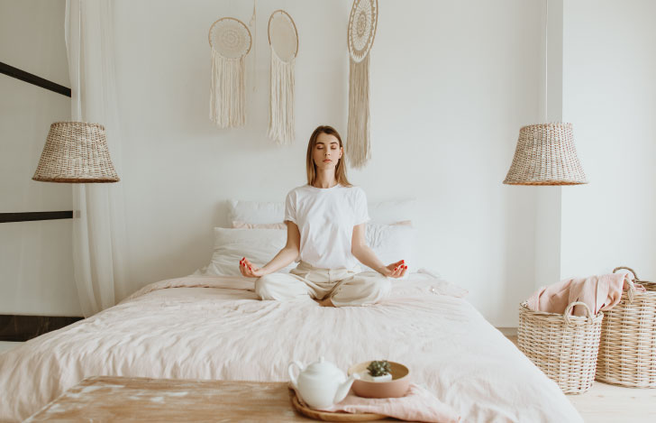 ベッドの上で瞑想を行う女性