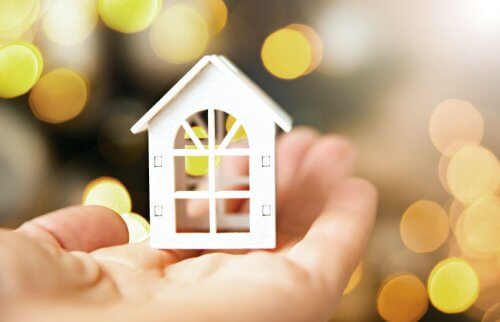 手のひらに乗った白い家の模型の写真