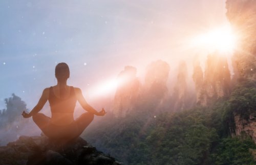 山で瞑想する女性と差し込む光