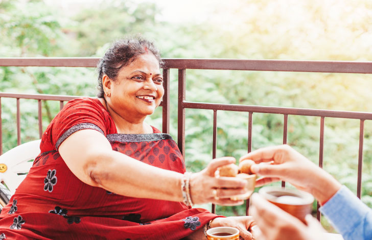 バルコニーにいるゲストにお茶を振る舞う女性