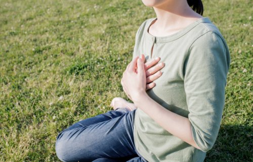 芝生の上で胸に手を当てて座る女性