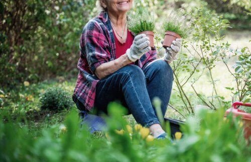 庭で植木鉢を両手に微笑む女性