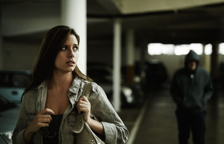 暗闇に怯えながら背後の人の気配を気にする女性