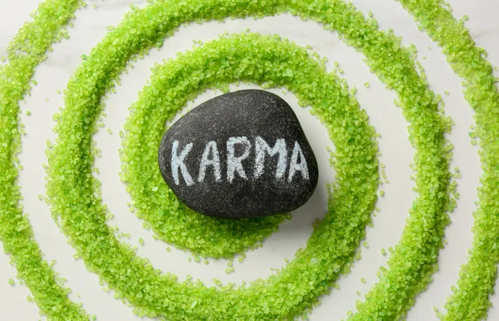 渦巻き状に置かれた緑の砂の上に置かれたKARMAと書かれた石