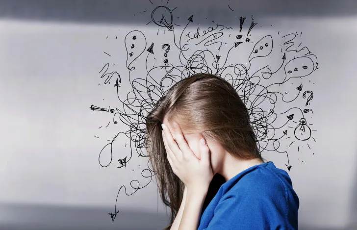 両手で顔を覆いごちゃごちゃとしたイラストが頭の周りに装飾された女性