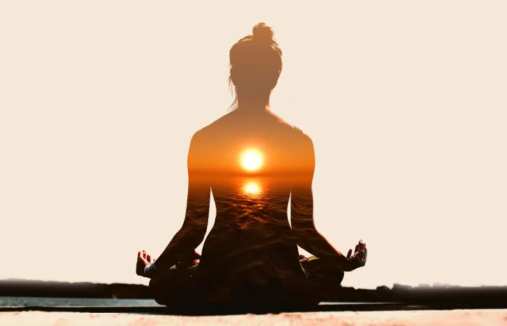 瞑想する女性のシルエットと夕日のダブルイメージ