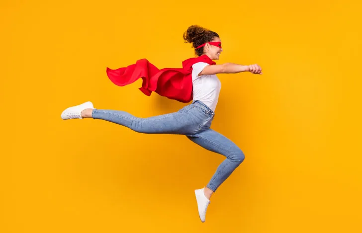 赤いマントと仮面をつけてジャンプする女性