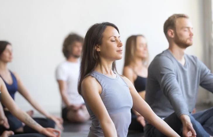 目を閉じて座るヨガクラスに参加している女性