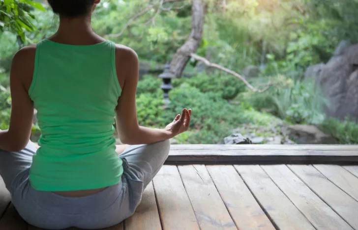 縁側で緑豊かな庭に向かって座る女性の後ろ姿