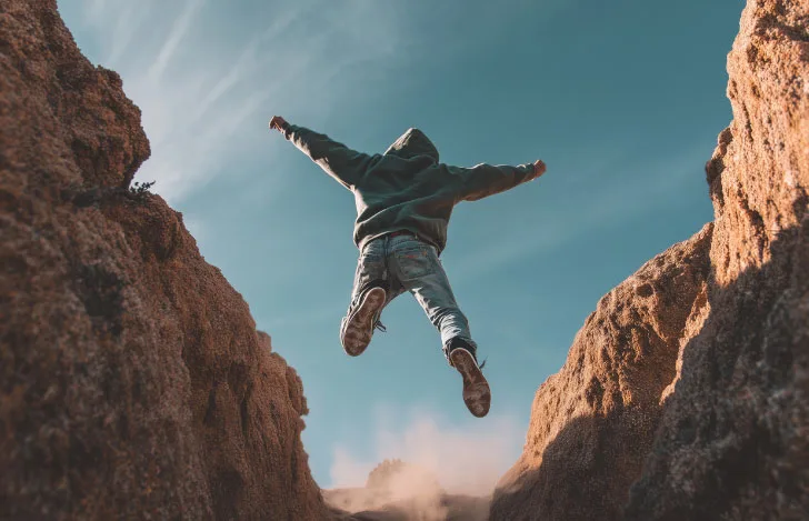 崖から飛び降りる男性の後ろ姿