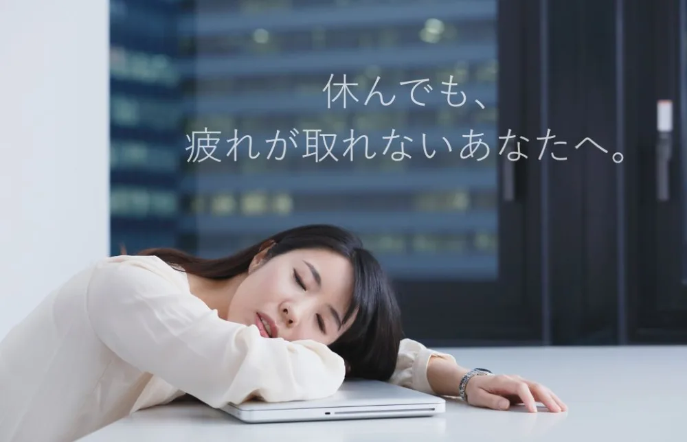 白い服を着た、女性が机に突っ伏している。