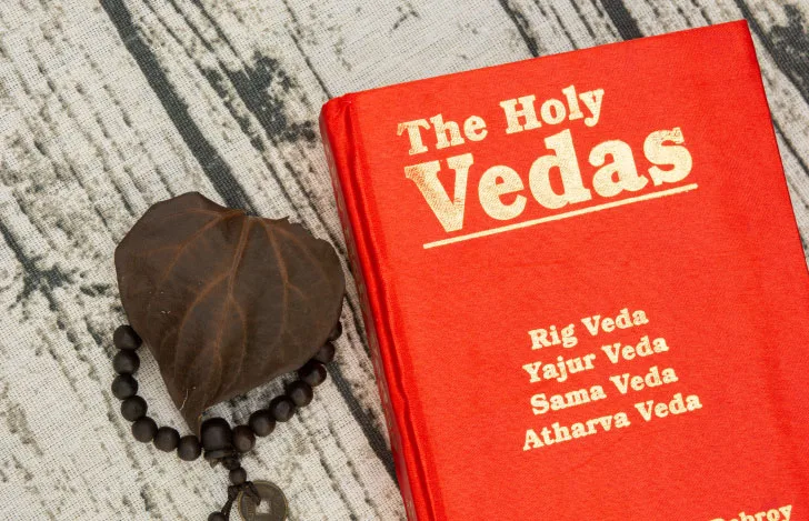 机の上に置かれた『ヴェーダ』の経典と数珠