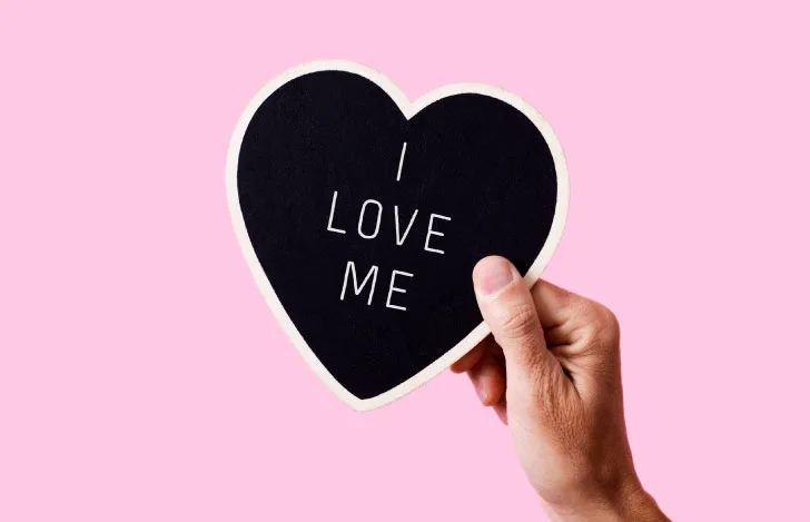 I LOVE MEと書かれたハートのカードを持つ人の手元